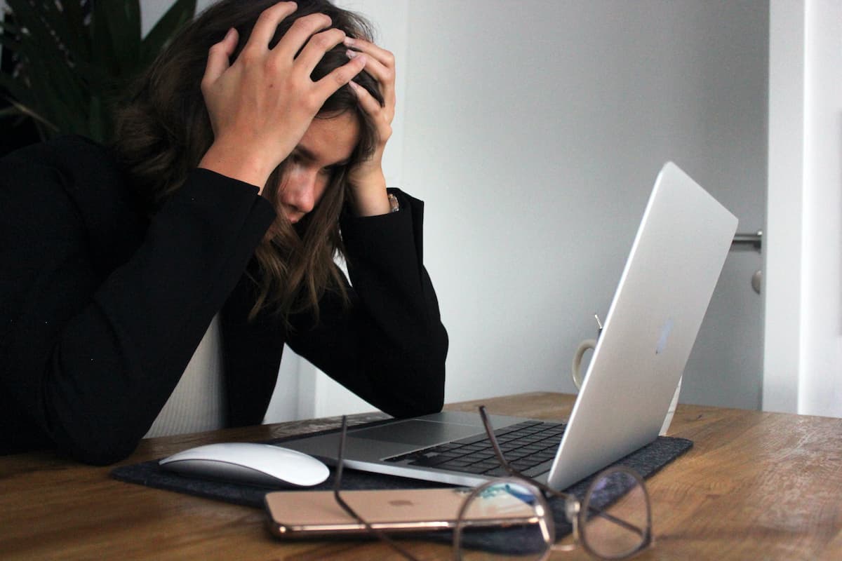 Frustrated developer looking at her laptop with her hands on her head.