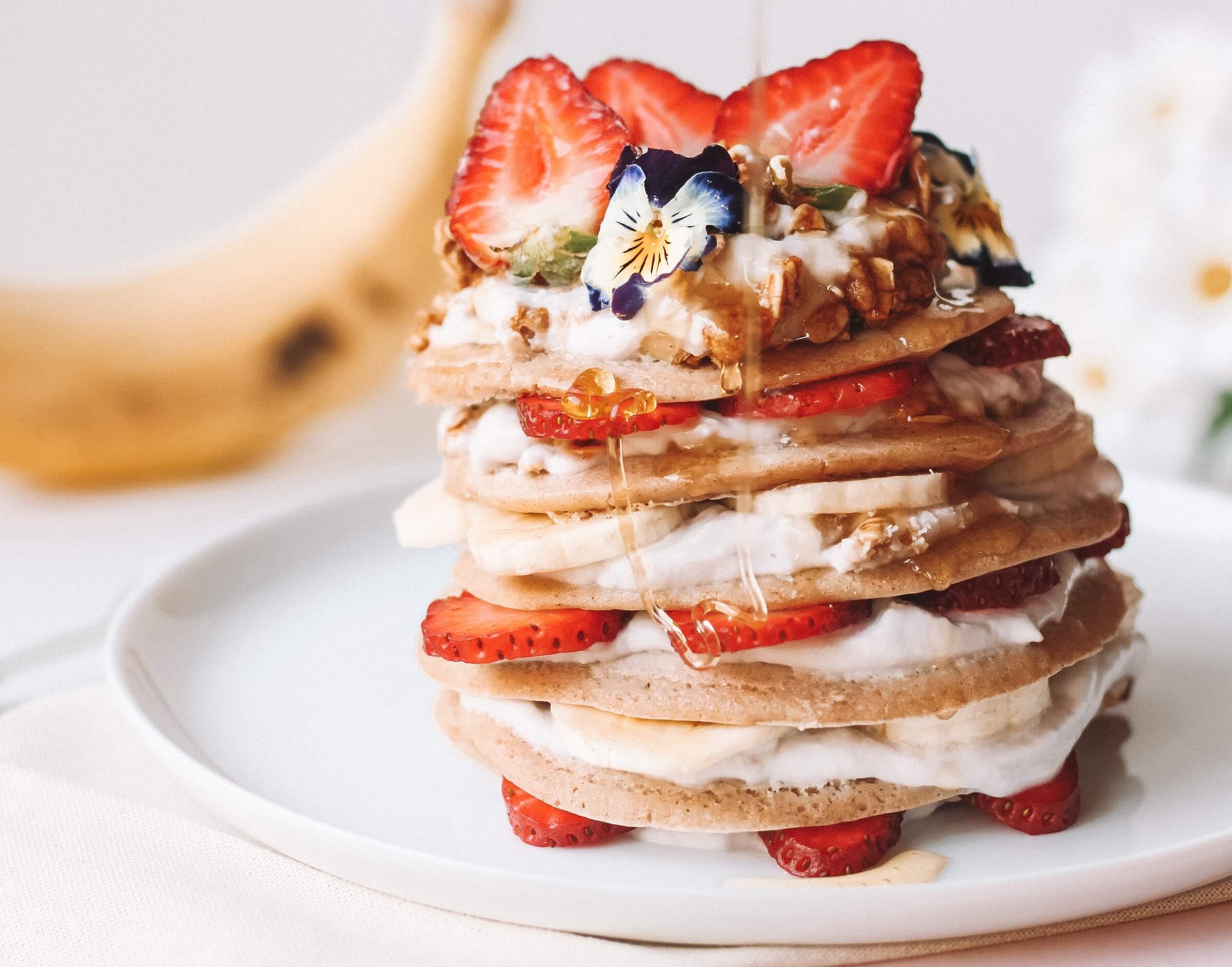 Stack of pancakes with cream and strawberries
